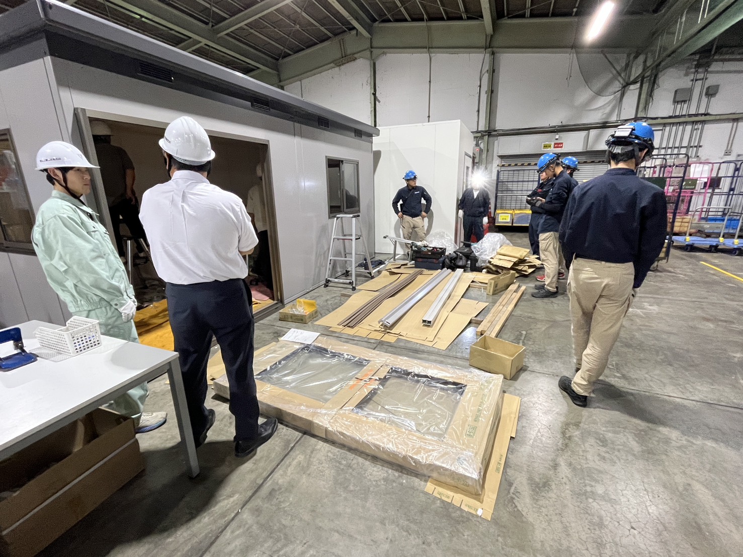 ヘルメットを着用し、現場で説明を受ける見学者と社員